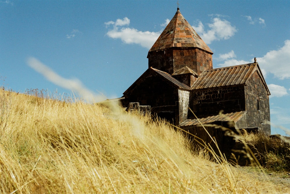 an old church on a hill with tall grass