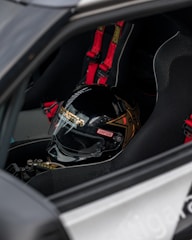 Close-up of a racing helmet and gloves resting on a motorcycle seat.