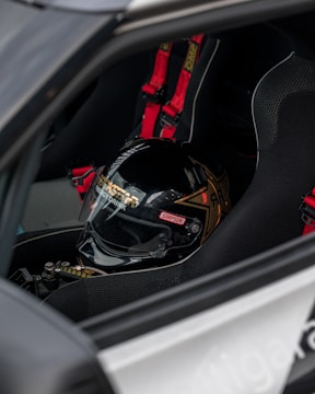 Close-up of a racing helmet and gloves resting on a motorcycle seat.