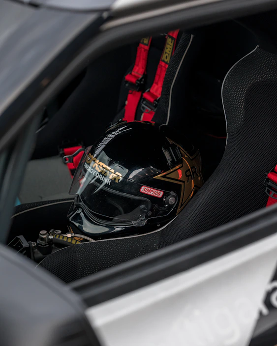 Close-up of a sleek, aerodynamic racing helmet with vibrant motorsport decals resting on a checkered flag.