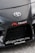 The image features the front part of a car with a focus on the bumper and grill area. Prominently displayed is the Toyota logo in the center of the car's hood. Nearby, there are several decals, including the words 'TENACI Parts for Racecars' in white with a red gear graphic, and 'altigarasjen.no' along with the 'Pandem' logo.