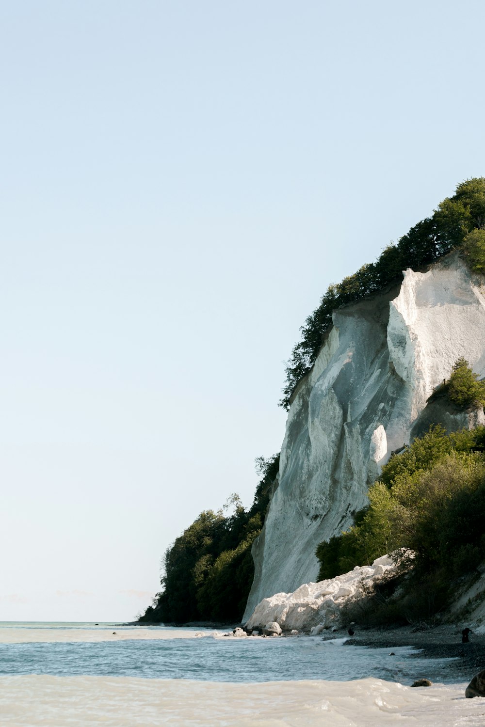 a beach with a cliff and a body of water