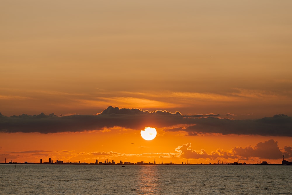 a large body of water with a sunset in the background