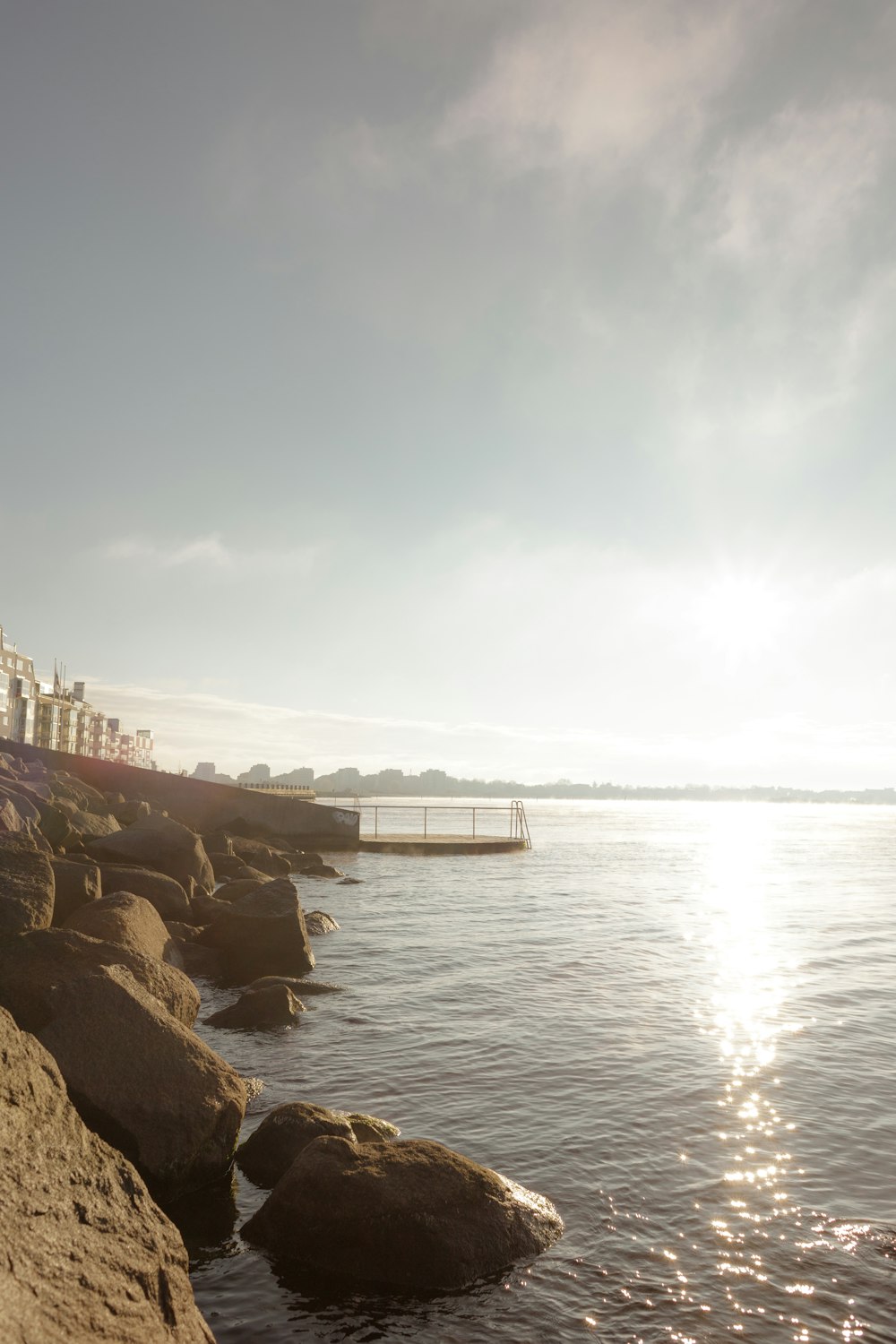 the sun is shining over the water and rocks