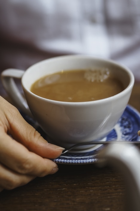 A cozy scene featuring a hand holding a sleek, modern coffee cup with steam rising, set against a warm wooden table.