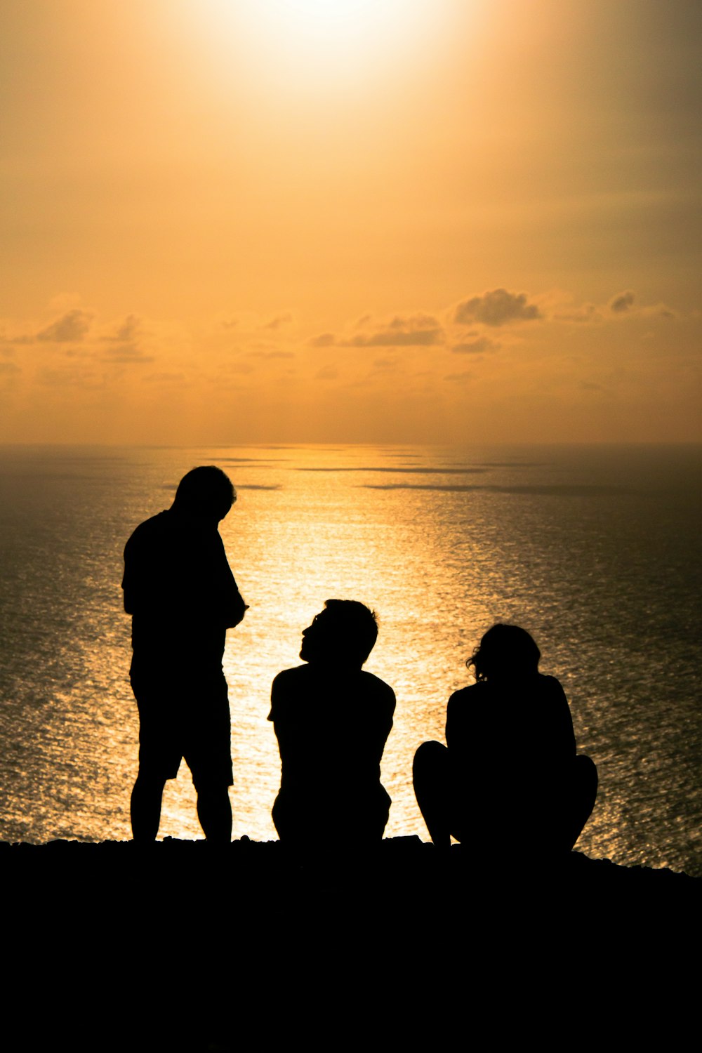 Un grupo de personas sentadas en la cima de una playa junto al océano