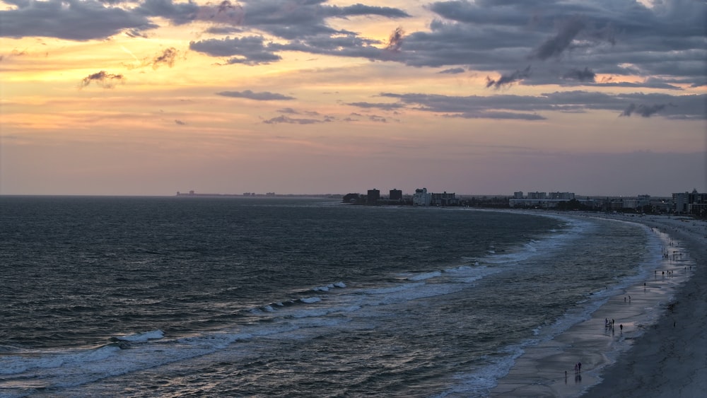 a view of a beach at sunset with a city in the distance