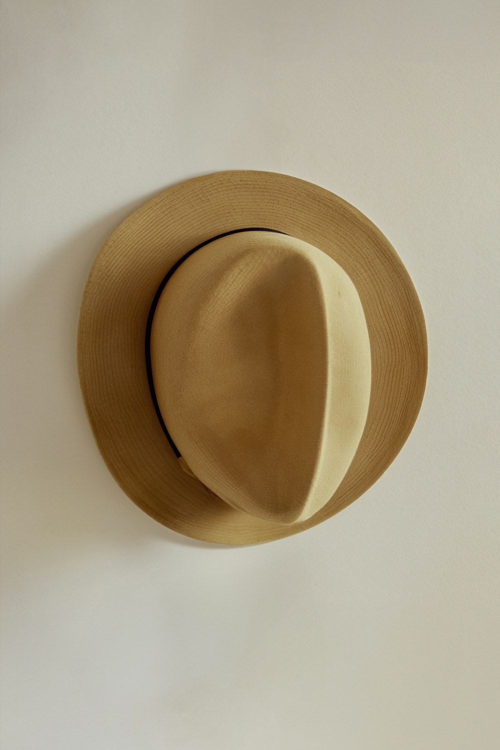 a tan hat hanging on a white wall
