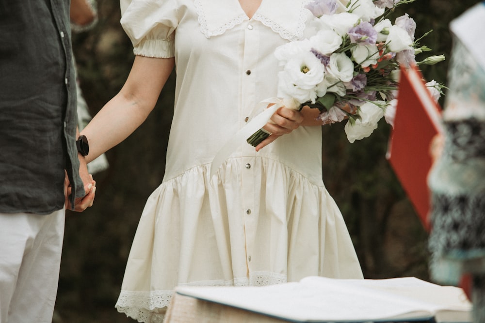 a woman in a white dress holding a bouquet of flowers