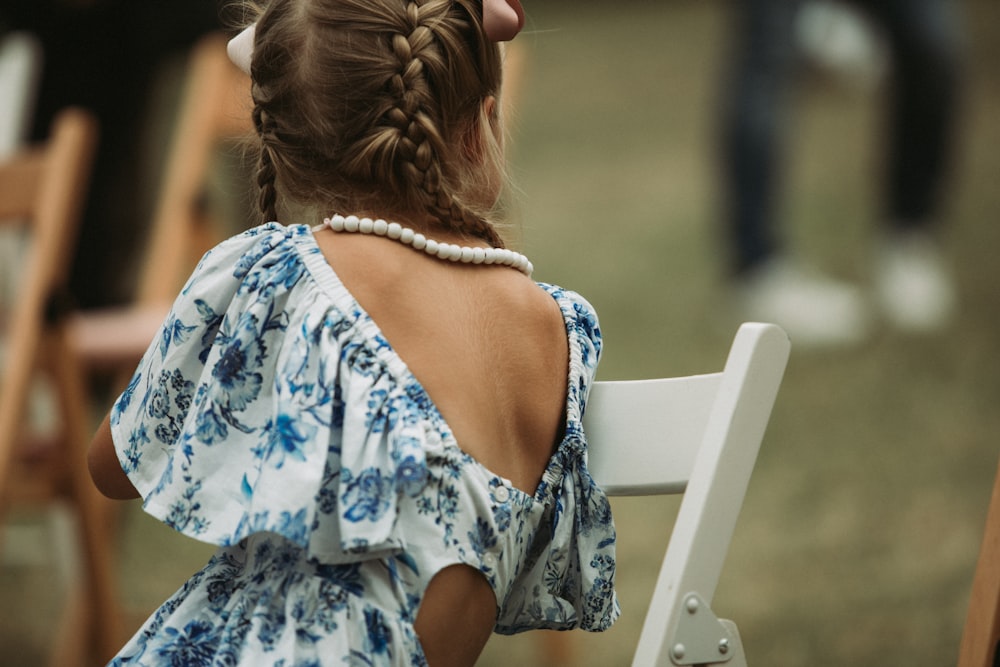 a little girl sitting on a white chair