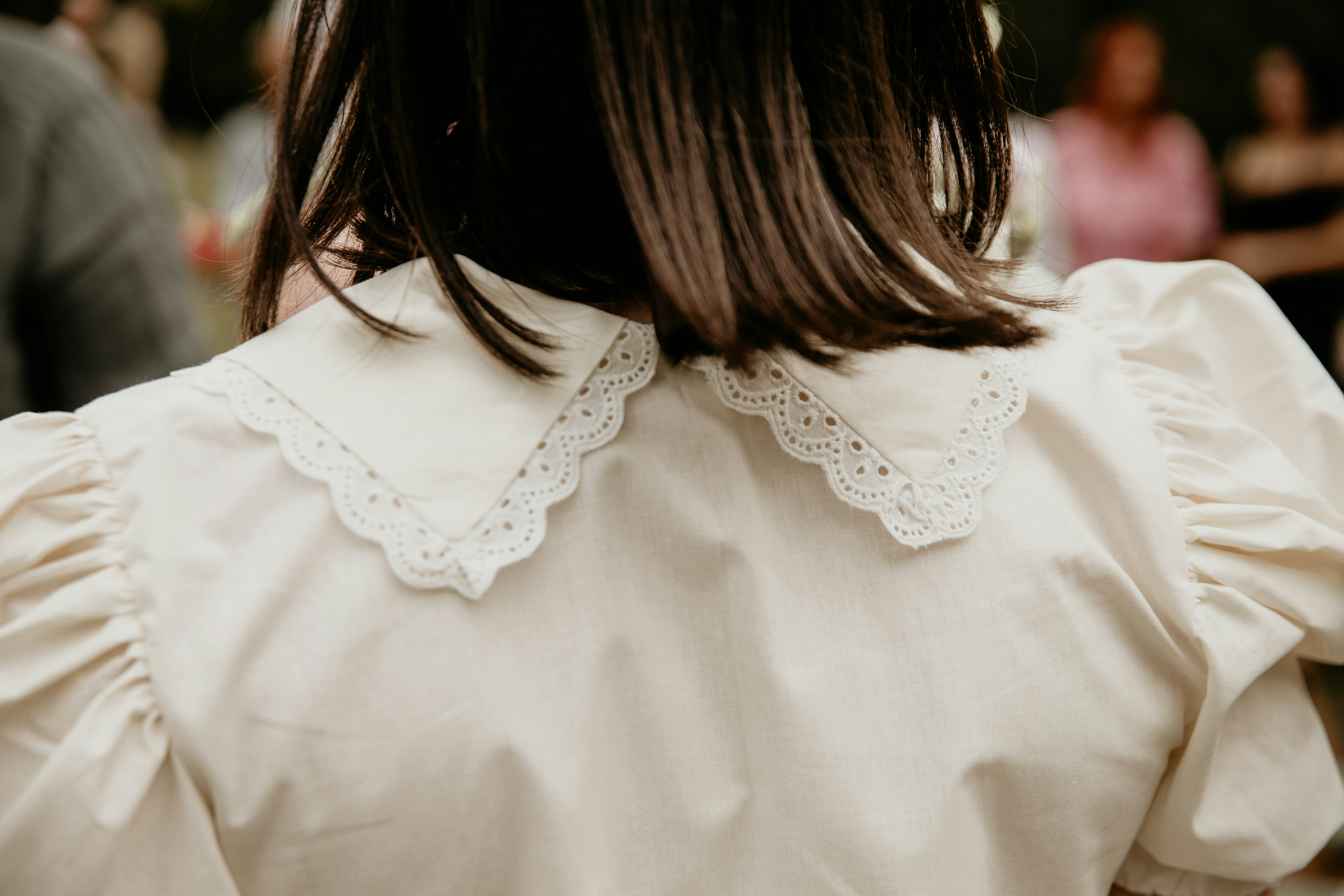 a woman wearing a white blouse with a scalloped collar