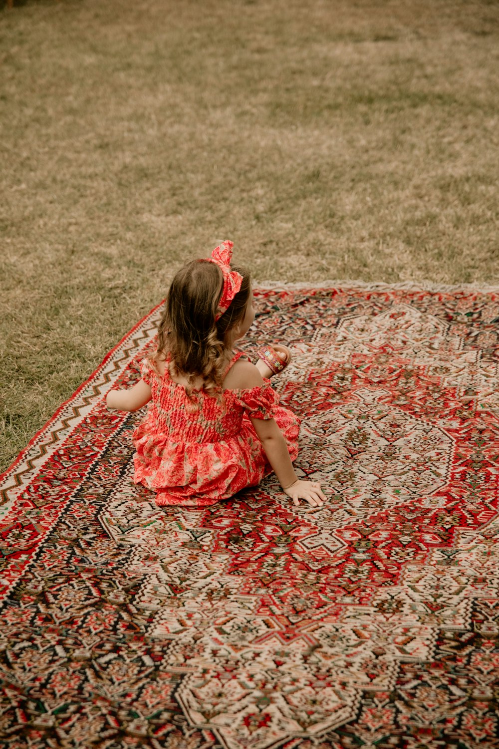 a little girl sitting on top of a rug