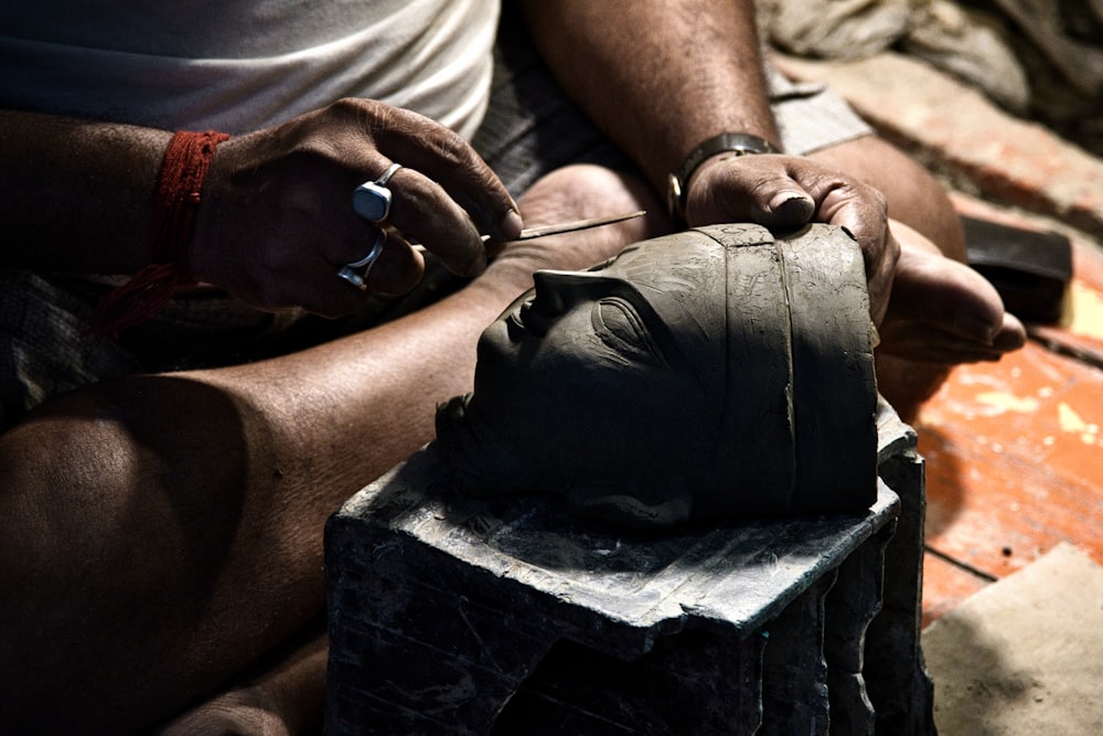 a man is working on a statue with a pair of scissors