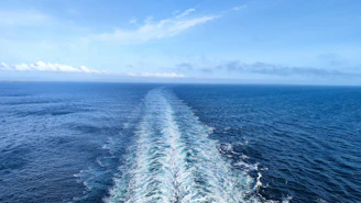 A massive oil tanker cutting through deep blue ocean waters under a clear sky.
