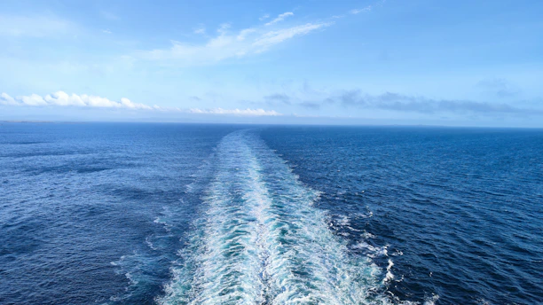 A massive oil tanker cutting through deep blue ocean waters under a clear sky.