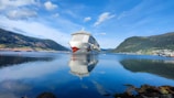 A majestic cruise ship sailing past towering fjords under a clear blue sky.