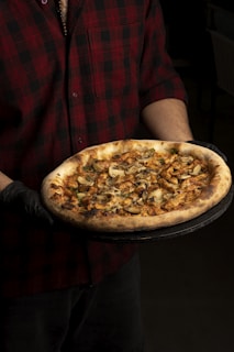 a man is holding a pizza on a tray