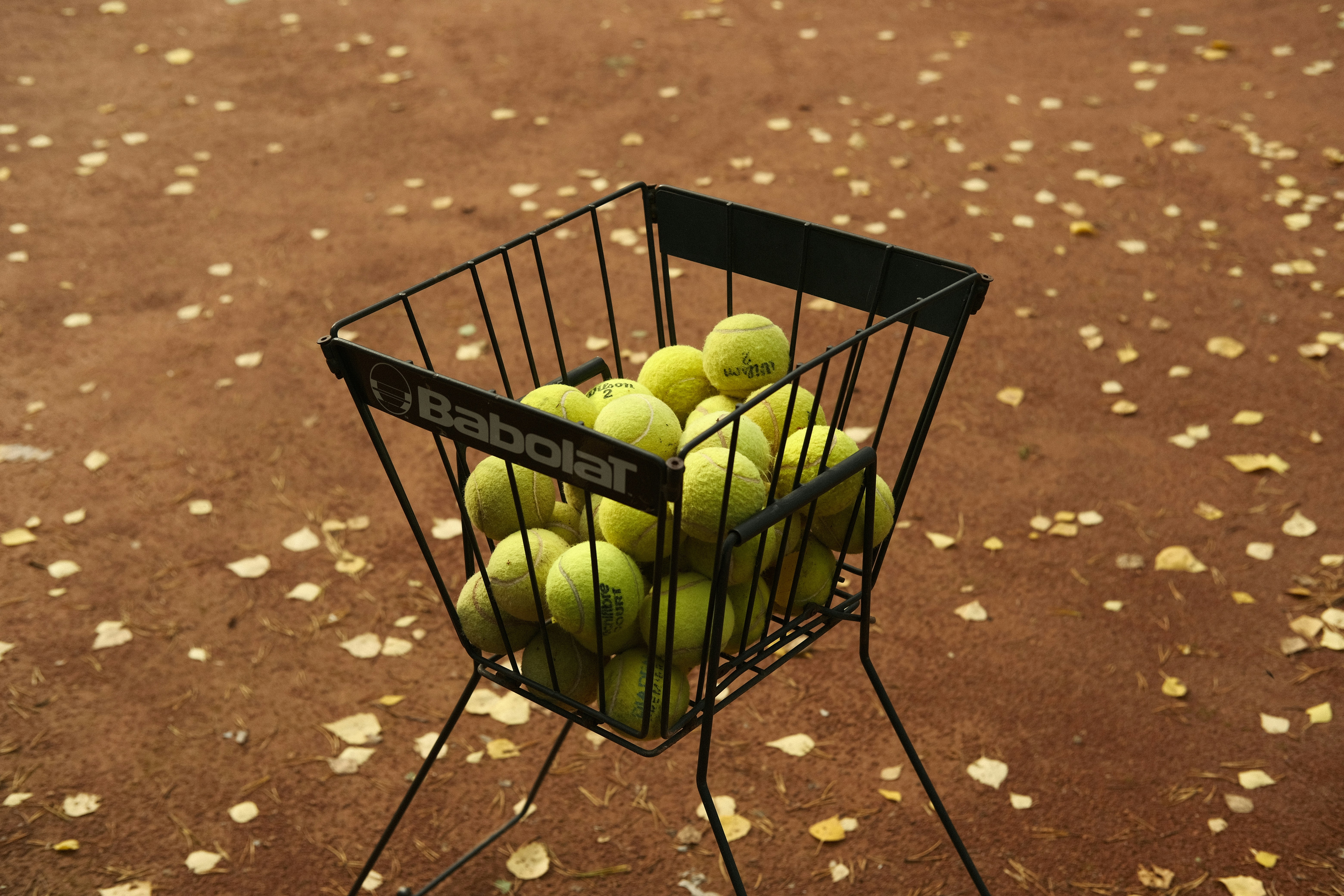 a basket of tennis balls sitting on top of a metal stand