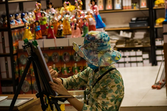 A designer sketching a hat with colorful materials around.