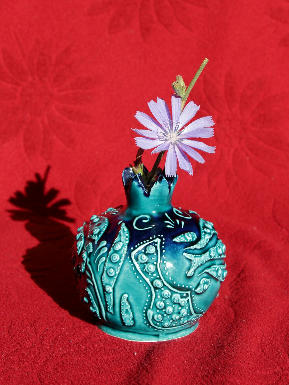 a blue vase with a purple flower in it