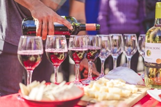 a person pouring a glass of wine at a table full of wine glasses