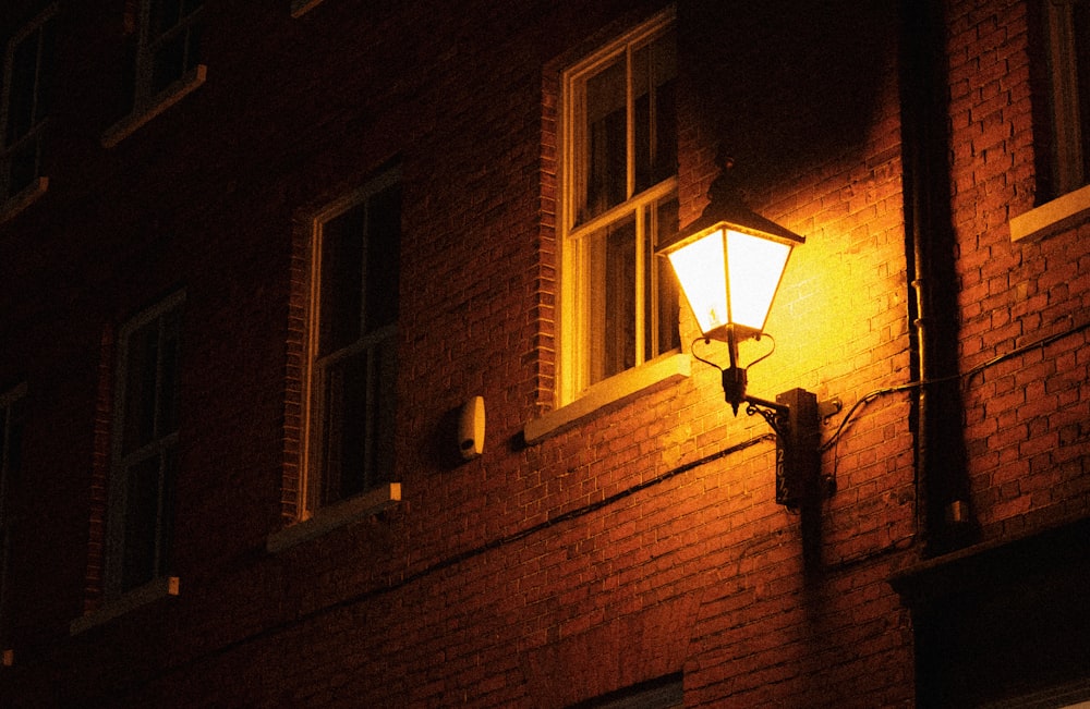 a street light on a brick building at night