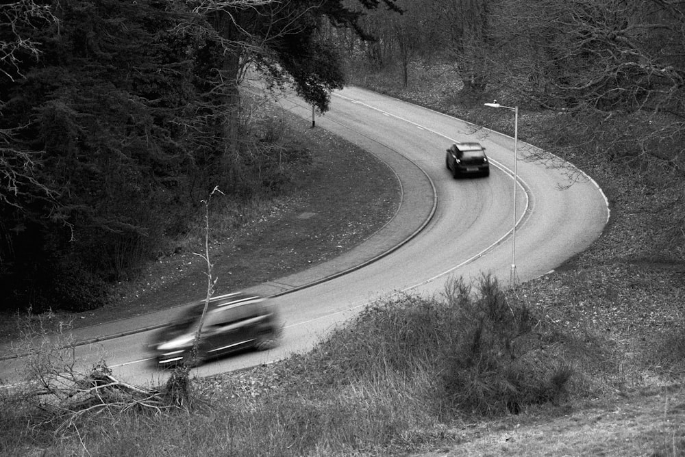 a couple of cars driving down a winding road