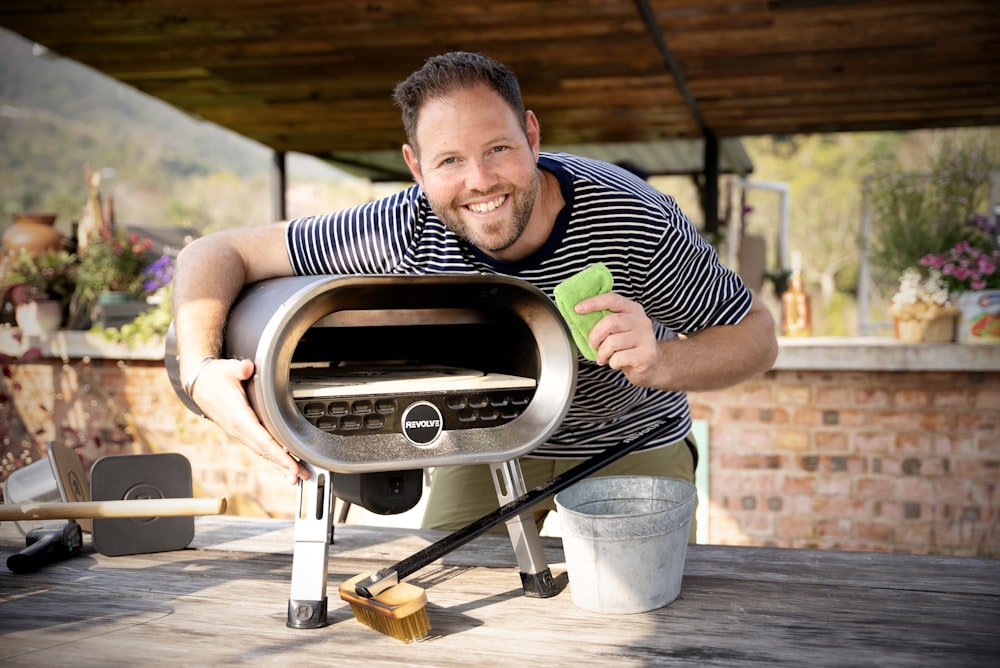 a man holding a green object in front of a bbq