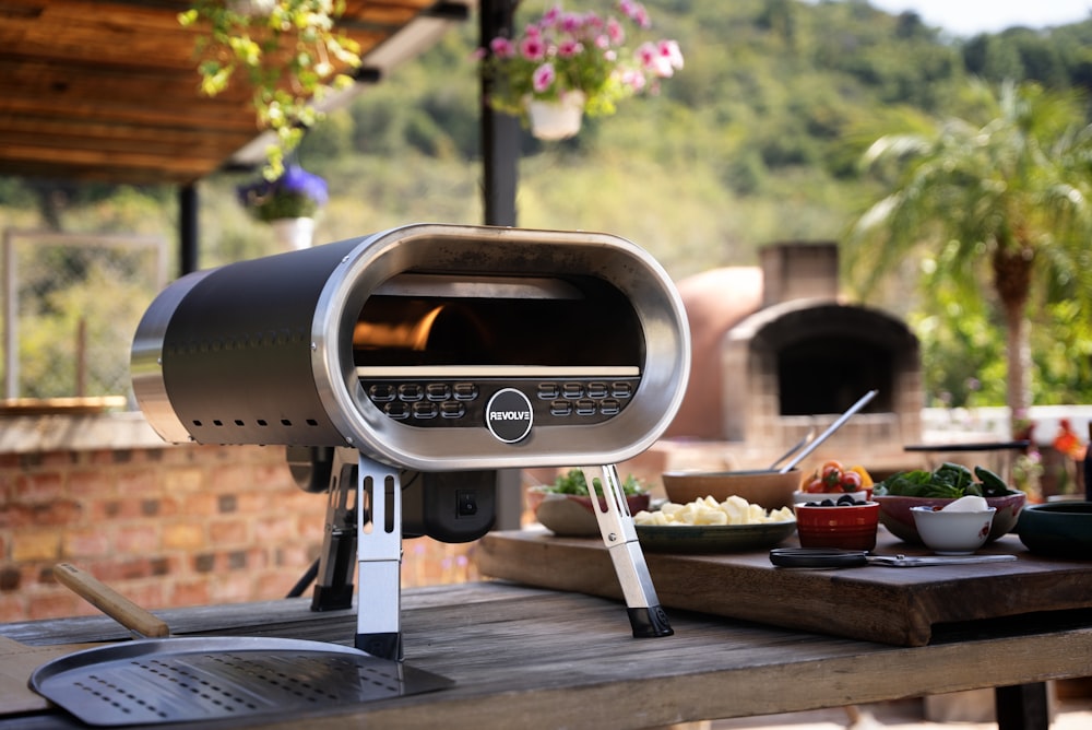 an outdoor grill with food on a wooden table