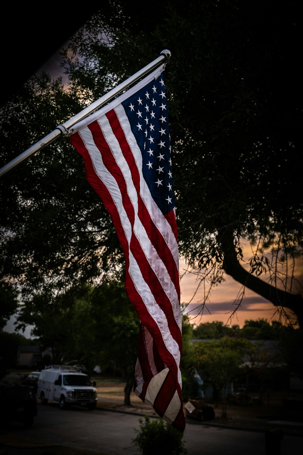 a large american flag hanging from the side of a tree