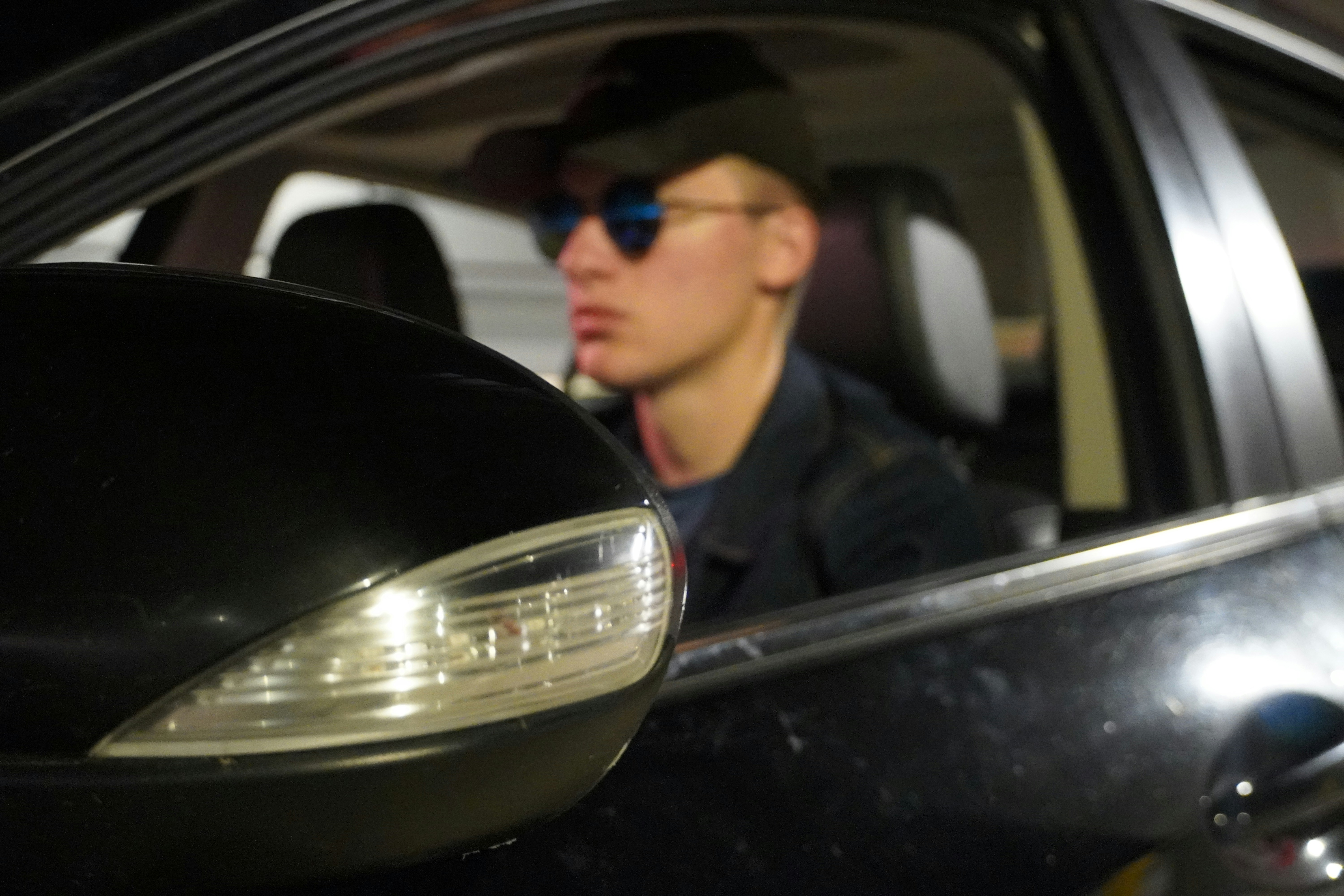 Un hombre sentado en un coche con gafas de sol y un sombrero