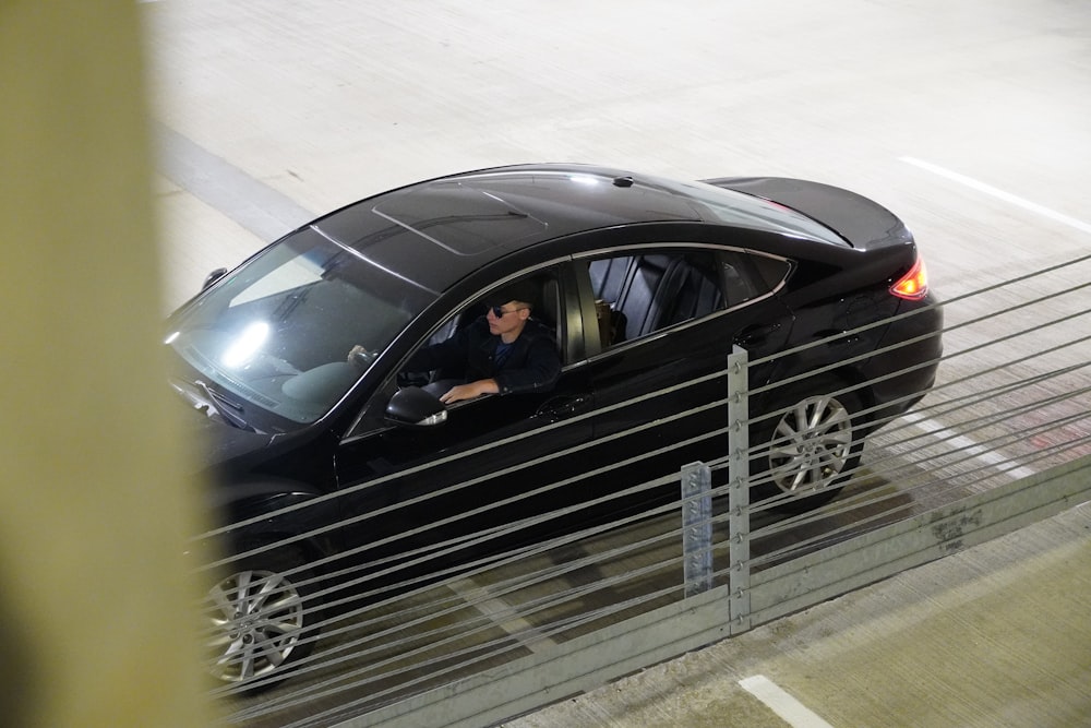 Ein Mann, der ein schwarzes Auto auf einer Straße fährt