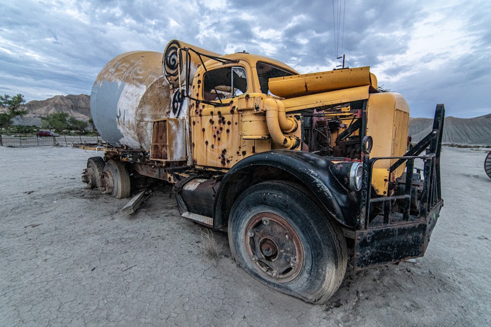 a large yellow truck parked on top of a dirt field