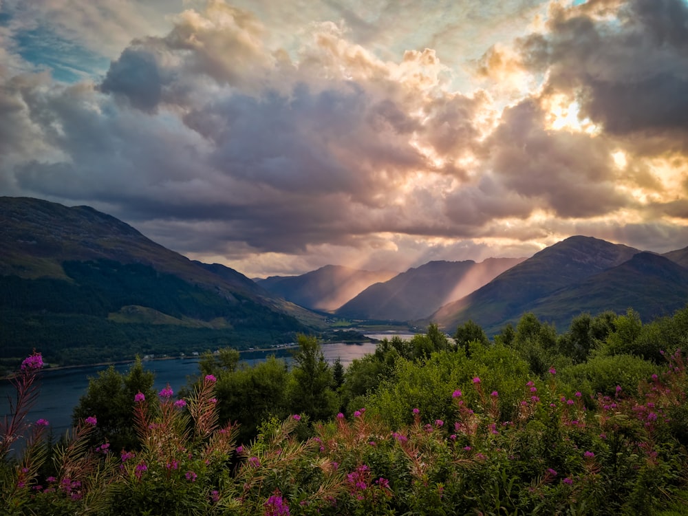 the sun is shining through the clouds over the mountains