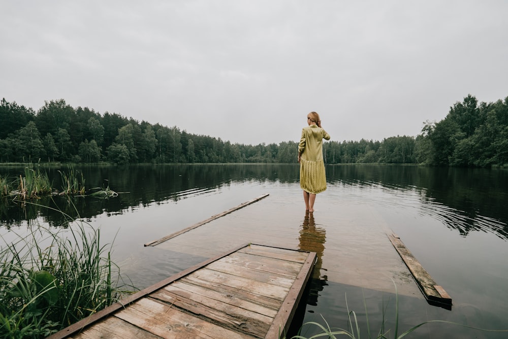 a woman in a yellow dress standing on a dock