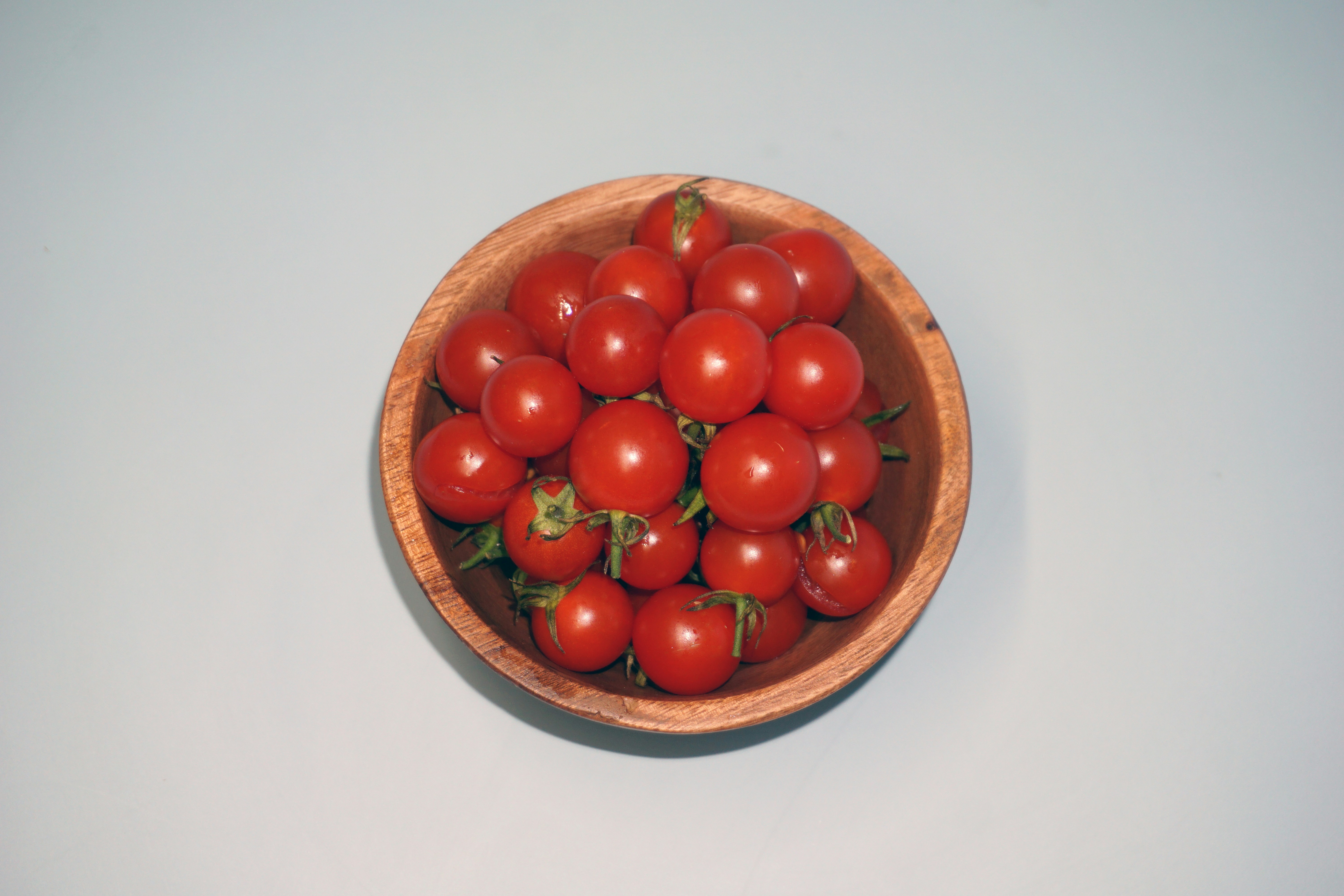 a wooden bowl filled with lots of red tomatoes, Crimson Delights: Cherry Tomatoes by Raju C Reddy Raju C Reddy