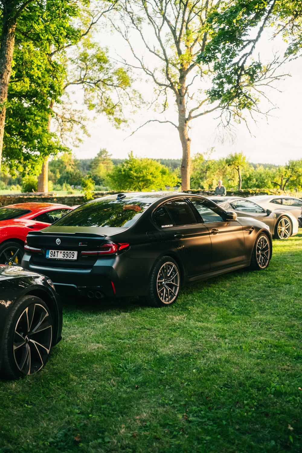 a group of cars parked on top of a lush green field