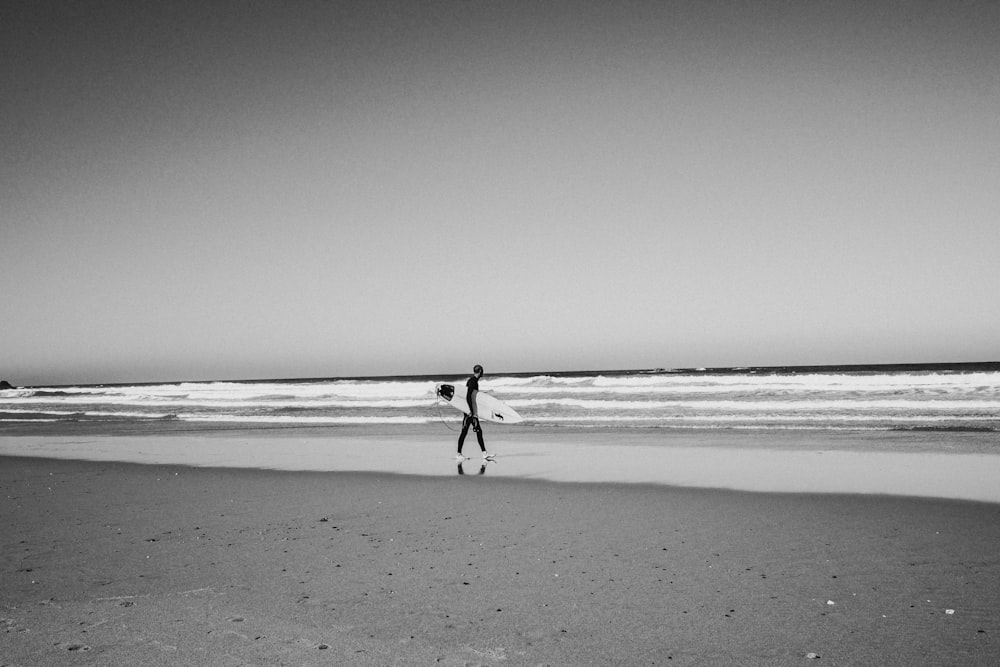 a person standing on a beach with a surfboard