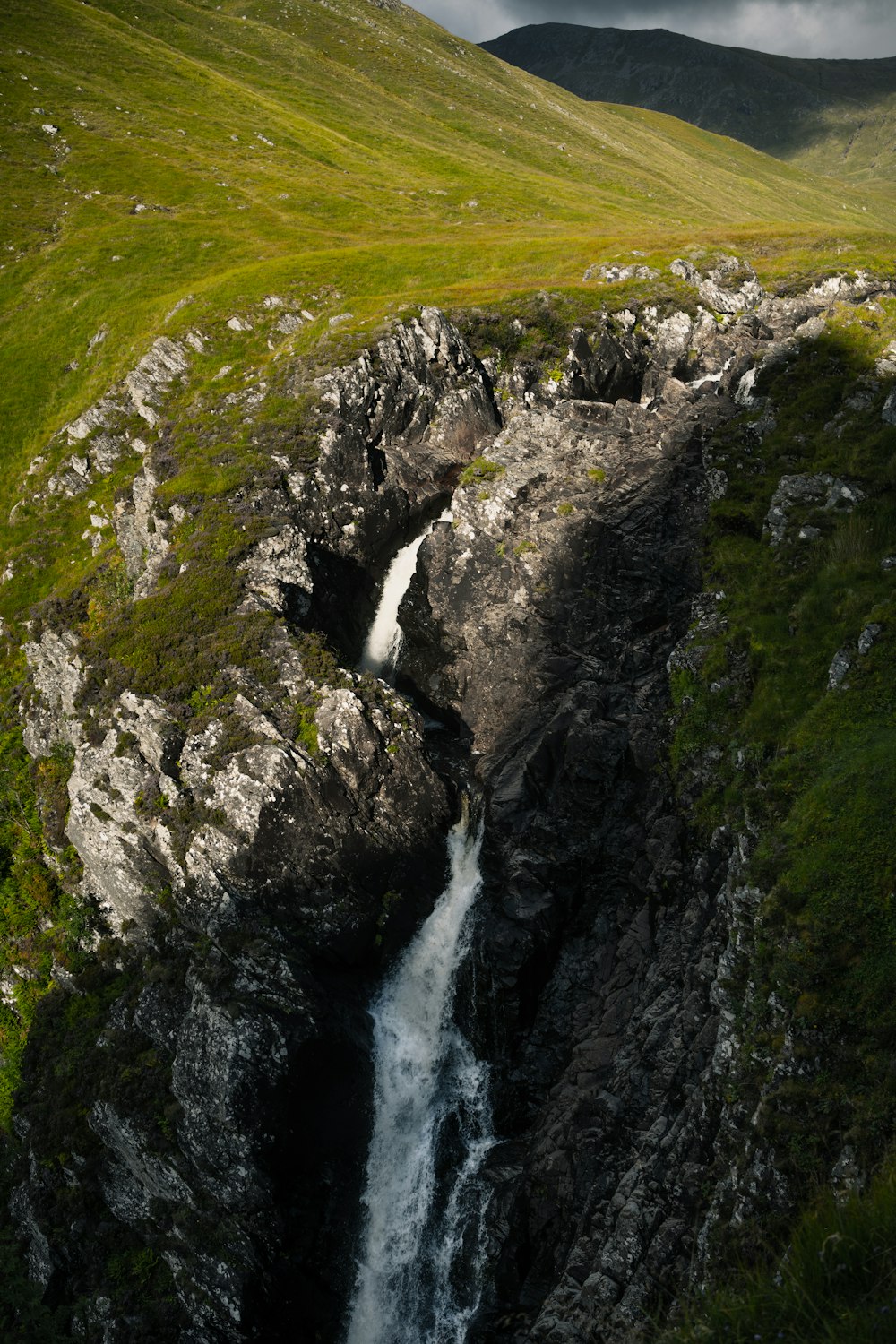a small waterfall running through a lush green hillside