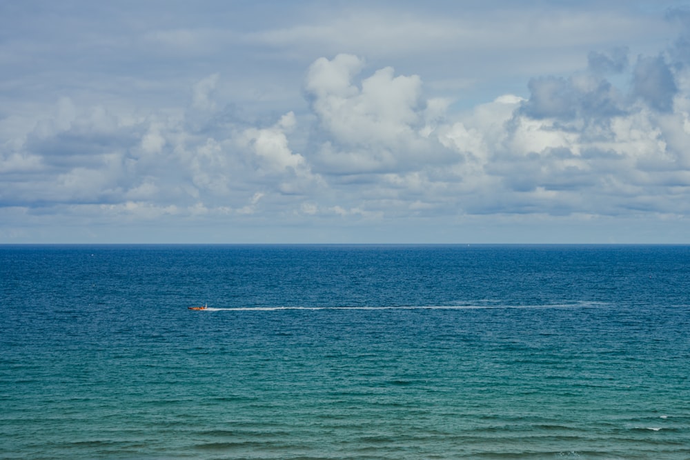 a boat in the middle of the ocean on a cloudy day