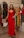 Young woman smiling while trying on a colorful dress in a boutique.