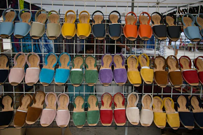 Colorful women's sandals and heels showcased on a bright, sunlit rack with floral accents.