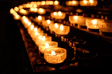 Artisan candles flickering gently in elegant black and gold holders, casting a warm glow on a sleek surface.