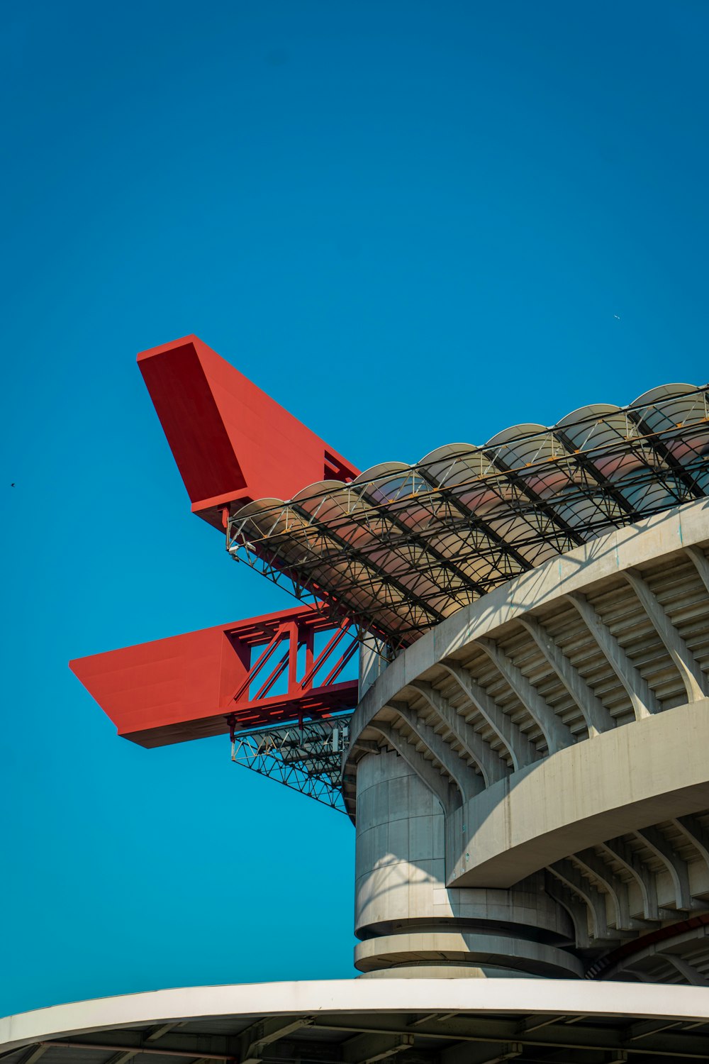 a red airplane is flying over a stadium