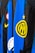 Close-up view of a sports jersey featuring bold vertical stripes in blue and black, adorned with a prominent yellow logo featuring a star on top. Additional elements include a Nike swoosh in yellow, a circular emblem with red, white, and green colors, and a section with black stars on white.