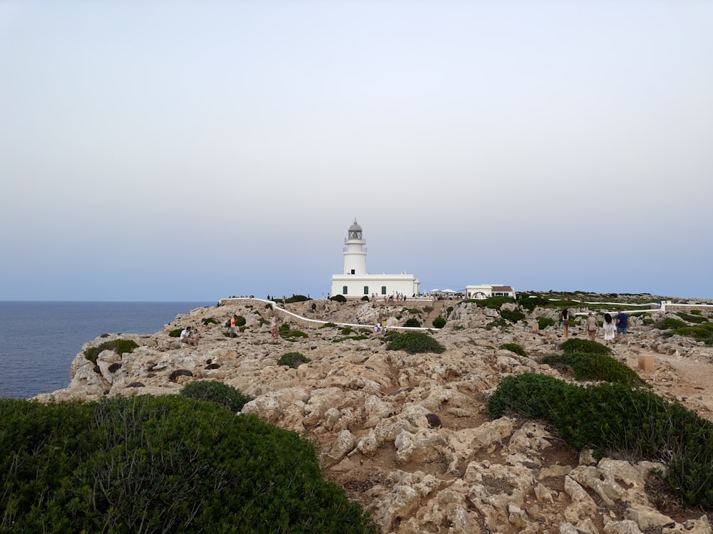 a white lighthouse on a rocky cliff by the ocean