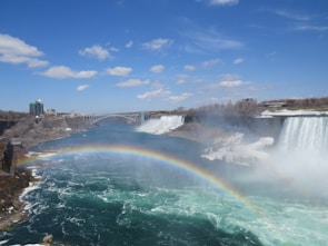 A vibrant shot of Niagara Falls under a rainbow on a sunny day.