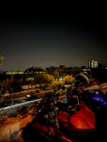 A motorcycle parked near a café, with a city skyline in the background.