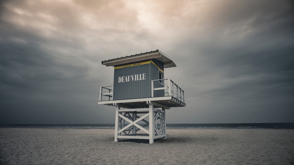 uma torre salva-vidas sentada no topo de uma praia de areia