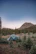 A sturdy Campora camping cot pitched on rocky terrain surrounded by pine trees.